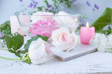 Spa still life with roses and candles on white wooden background