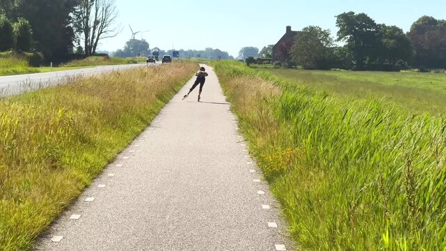 Person on inline skates, skeelers, roller blades, skates in summer on bicycle lane, bike path in Friesland, Frisia, Fryslan, the Netherlands, Holland, practice for winter ice skating