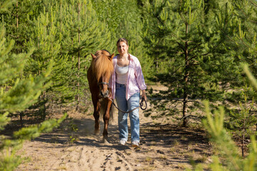 Woman with Icelandic horse between pines at summer evening