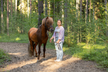 Woman with Icelandic horse on path middle of the forest