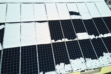 Aerial view of house roof with solar panels covered with snow melting down in winter end for...
