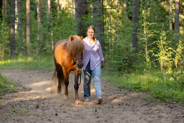 Woman with Icelandic horse on path middle of the forest