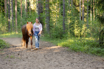 Woman with Icelandic horse on path middle of the forest