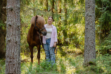 Woman with Icenlandic horse in forest with sunset on behind