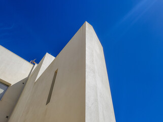 Modern building corner with a minimalist design against a deep blue sky
