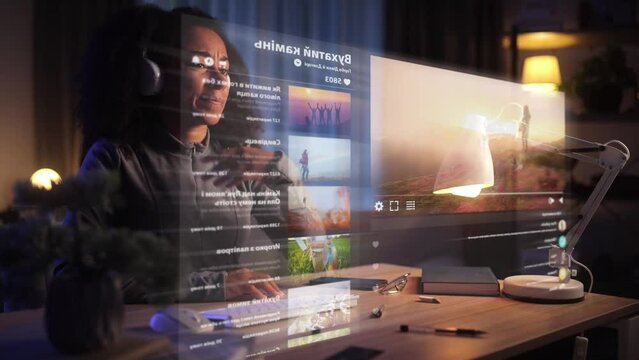 A young woman switches between workspaces on a holographic screen. Focused individual watching and managing multiple video streams on transparent screens at a modern desk