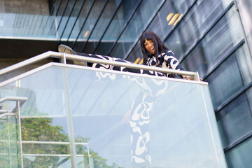 Energetic dancer leaning the leg on a building rail performing