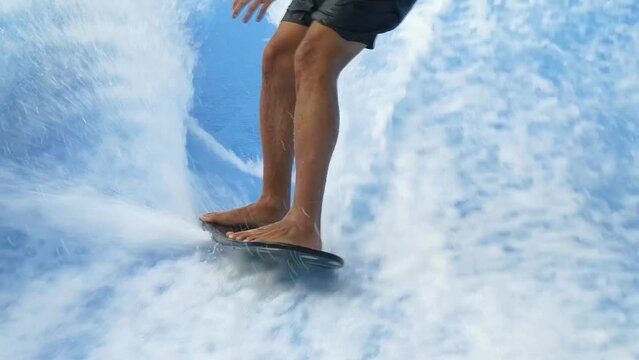 Young man surfing on a wave simulator at a water amusement park