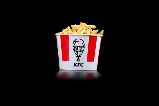 Minsk, Belarus, July 05, 2024: black background, smoke, steam, night. French fries. Lots of hot KFC shortcuts cut into strips in a KFC Kentucky Fried Chicken fast food bucket