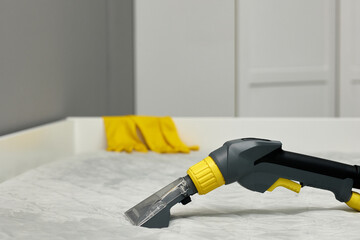 A professional cleaning vacuum cleaner handle with a nozzle placed on a stylish, modern bed in a tidy room. The scene conveys a sense of cleanliness, modernity, and efficiency in household chores.