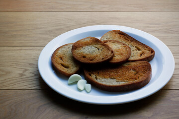 Five slices of fried bread with peeled garlic on white plate. Traditional Czech fried bread (called 