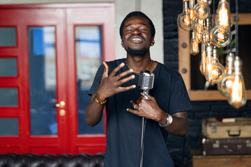 Handsome attractive african american singer, man singing in retro microphone in studio music recording