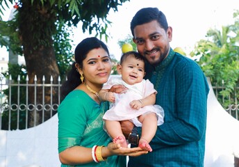 South asian young couple having fun time with their baby girl in a park , family togetherness...