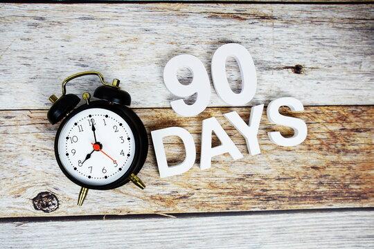 90 Days and alarm clcok alphabet letters on wooden background