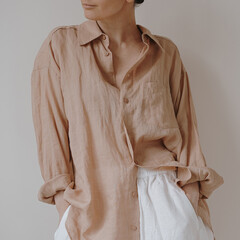 Casual and relaxed style featuring a light brown linen button-up shirt with rolled sleeves paired...