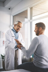 Obraz premium Hand, man and doctor with patient for inspection of wrist checkup, arthritis and exam for diagnosis assessment. Medical, people and joint pain from accident, nerve problem and healing arm of wellness