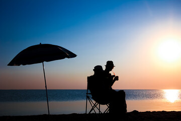 A Happy couple by the sea at sunset on travel silhouette in nature