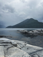 Gloomy Nordic fjords and rocks. Vertical photo with mystic landscape in Norway.