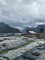 Gloomy Norway hut in front of fjords in July