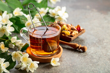 Cup of jasmine tea and fresh jasmine flowers on a stone table.