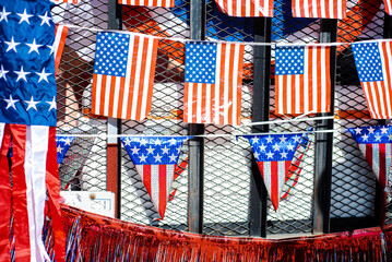 Dense of triangle rectangle American flags string hanging on back of steel mesh utility trailer...