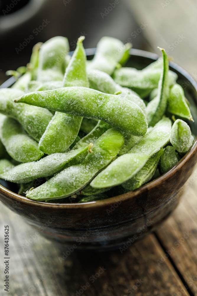 Poster green edamame pods. fresh soybeans in bowl on wooden table.