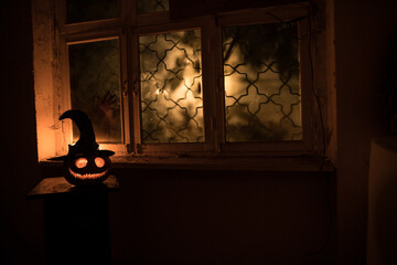 Scary Halloween pumpkin in the mystical house window at night or halloween pumpkin in night on room...