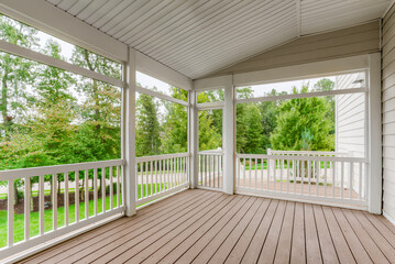 Screened-In Wooden Porch With White Railings Overlooking Green Backyard Area
