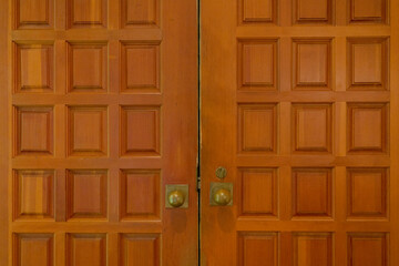 Fototapeta premium Vintage Wooden Double Front Doors With Intricate Square Panel Designs And Brass Knobs