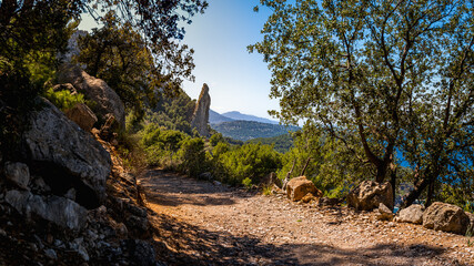 Camí de s'Illeta path on a sunny spring day framed by lush greenery and the impressive Es Penyal Bernat rock, showcasing Mallorca as a prime destination for nature lovers and outdoor enthusiasts.