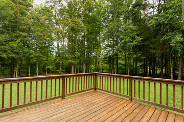 Wooden Deck Overlooking Green Backyard With Dense Forest In View