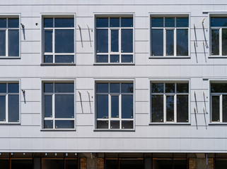 Obraz premium Several windows, a wall building with a gray facade. New windows have been installed in a house under construction with a light, ventilated facade. External front view, close-up.