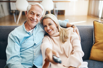 Mature couple, sofa and watching tv together for news, streaming movies and bonding in home. Lounge couch, man and woman with remote for television broadcast, change channel and series subscription