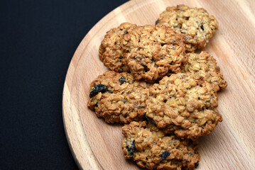 Oatmeal cookies on a board on a black background. A sweet snack. Lots of cookies.