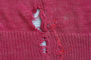 texture of torn cherry-colored woolen soft warm fabric of a women's old sweater with a pattern and...
