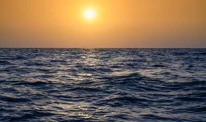 Warm waves of the Mediterranean Sea and sandy beach at sunset