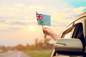 Waving the Tuvalu flag against the sunrise or sunset from a car driving along a country road....