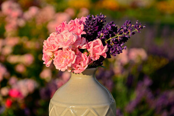 różowe róże i fioletowa lawenda w wazonie na rozmytym tle, róże i lawenda w małym wazonie na tle ogrodu, pink roses and purple lavender in a vase on a blurry background © kateej