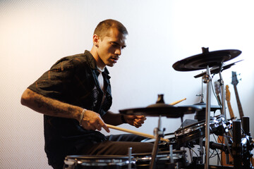 Young mixed race drummer playing drums in music studio 