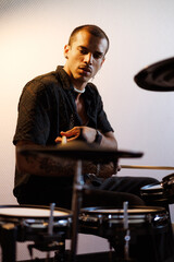 Stylish mixed race musician playing drums in music studio with lighting 
