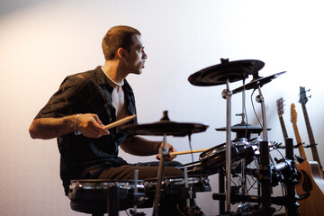 Focused mixed race drummer playing drums in music studio