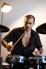 Portrait of stylish mixed race musician performing drums in music studio