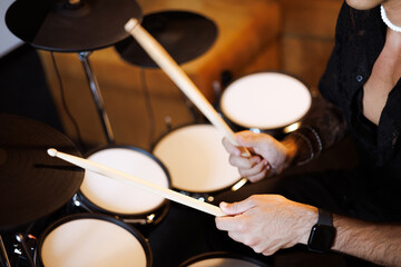 Partial shot of musician holding drumsticks near electric drums in studio