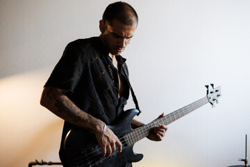 Young mixed race guitarist playing bass guitar in music studio