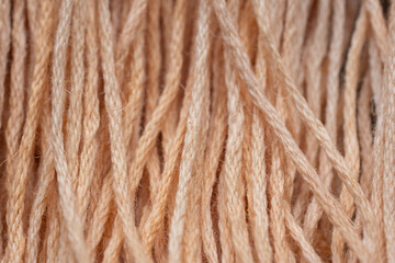 Beige strings creating a dense and intricate texture. The natural fibers exhibit a subtle range of tones, giving a warm and earthy feel to the composition. Perfect for textile and craft-related themes