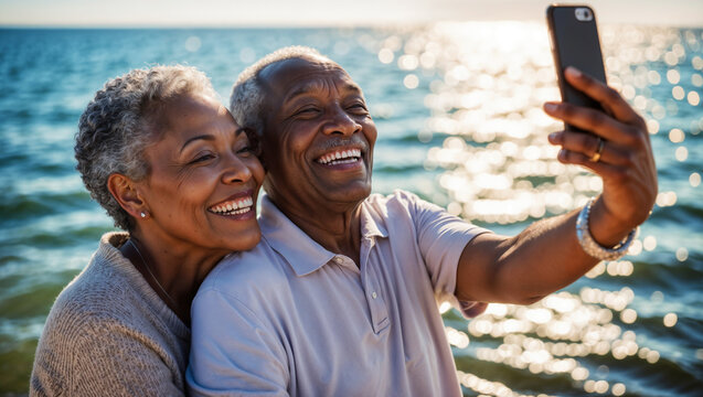 Coppia di anziani di origine afro americana si fanno un selfie con il cellulare e sorridono felici in riva al mare