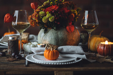 Atmospheric autumn elegant beautiful table setting with pumpkins for a wedding or thanksgiving family celebration. Fall decoration countryside rustic style, cozy home atmosphere , candles, wine