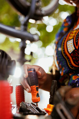 Detailed shot of african american person choosing expert work tools for yearly outdoor bike maintenance. Image showing closeup view hands gripping screwdriver for modern bicycle repair.