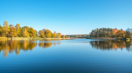 A serene lakeside scene with autumn foliage reflecting on the water, under a clear blue sky 
