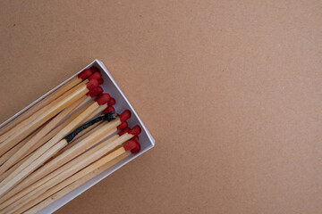 One burnt match among the whole ones. Scattered wooden matches without a box close-up. Design
